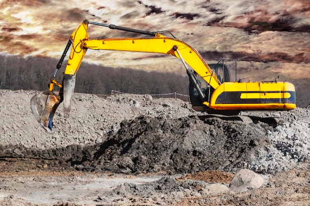 Un potente escavatore scava il terreno contro il cielo blu Lavori di sterro con attrezzature pesanti in cantiere