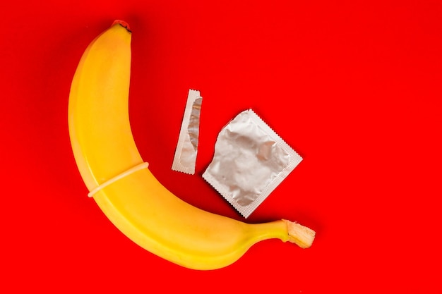 Un preservativo e una banana sesso sicuro Giocattolo del sesso su sfondo rosso