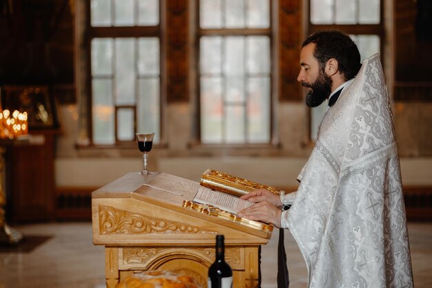 Un prete in una chiesa con una bibbia e un bicchiere di vino