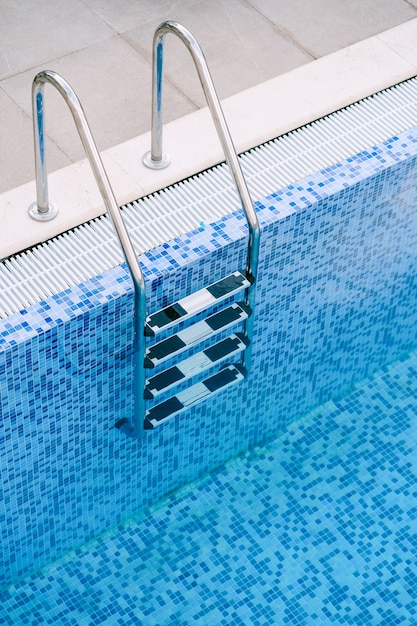 Un primo piano delle scale in piscina su uno sfondo di mosaico blu