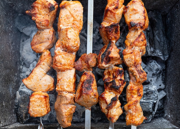 Un primo piano delle torte di maiale in salsa teriyaki è fritto su spiedini. Preparazione di uno shish kebab in una giornata estiva