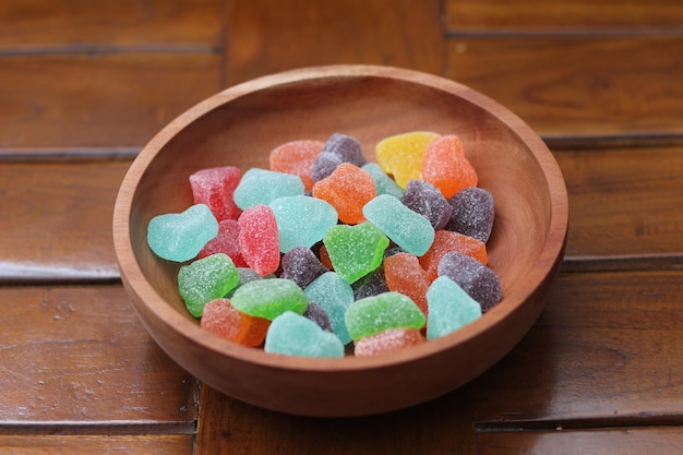 un primo piano di caramelle gommose di vari colori e sapori di frutta servite in una ciotola di legno