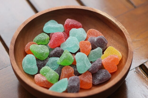un primo piano di caramelle gommose di vari colori e sapori di frutta servite in una ciotola di legno
