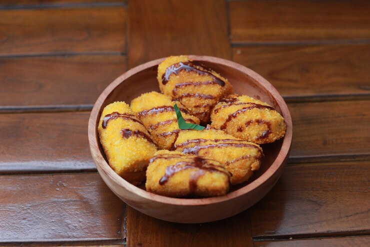 un primo piano di nuggets di banane con topping di salsa al cioccolato servito su una ciotola di legno foto concettuale di cibo