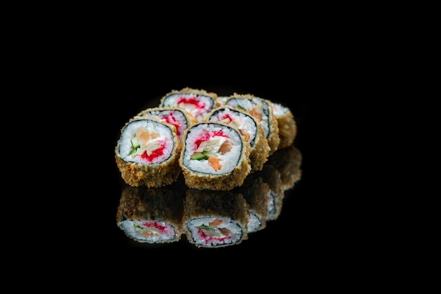 Un primo piano di rotoli di sushi fritto cibo isolato sulla riflessione nera