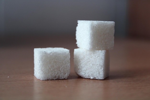 Un primo piano di tre zollette di zucchero bianco su sfondo sfocato