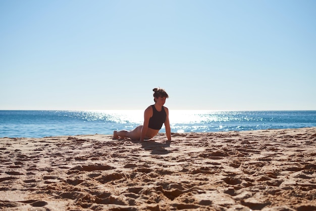Un primo piano di una giovane donna che fa yoga sulla spiaggia