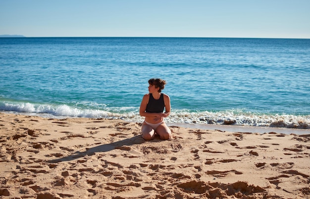 Un primo piano di una giovane donna seduta sulla spiaggia