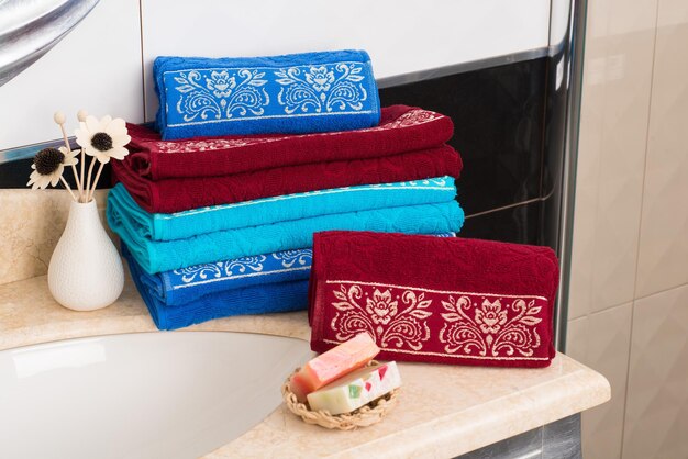 Un primo piano di una pila di asciugamani di bambù colorati piegati su un mobiletto del bagno
