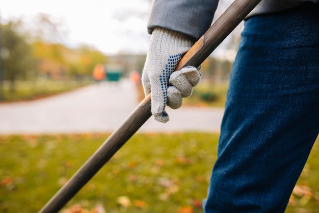 Un primo piano ha ripreso un uomo con un rastrello in mano che rastrellava le foglie nel parco autunnale.