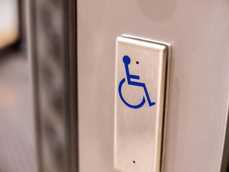 Un pulsante di metallo con un simbolo blu di sedia a rotelle su di esso oggetto primo piano nessuno accessibilità per disabili