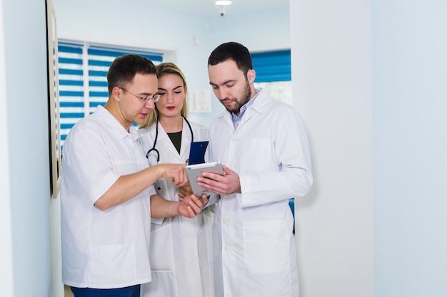 Un punto di vista dell'angolo alto di tre medici in camice che hanno conversazione al corridoio dell'ospedale