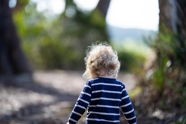 un ragazzino biondo che cammina in una foresta in un'escursione in primavera