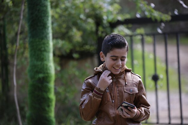 Un ragazzino carino che cammina nel parco forestale all'aperto