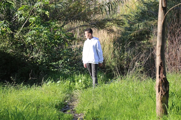 Un ragazzino carino che cammina nel parco forestale all'aperto