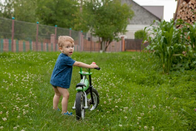 Un ragazzino carino con una bicicletta vicino alla casa, uno sport per bambini, una famiglia attiva per strada.