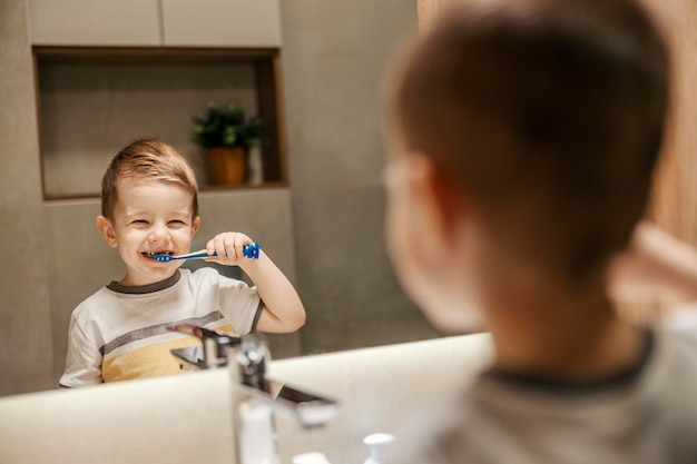 Un ragazzino carino sta pulendo e lavandosi i denti in bagno