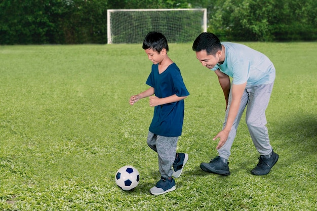 Un ragazzino che gioca a calcio con suo padre in studio