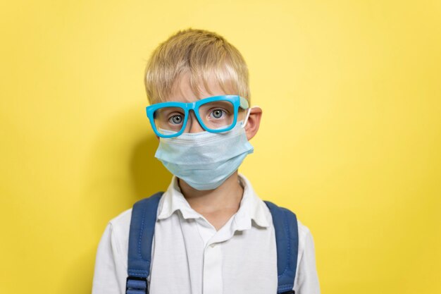 Un ragazzino con gli occhiali e una maschera protettiva respiratoria.