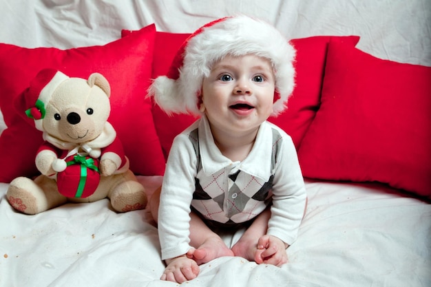 Un ragazzino con un berretto rosso mangia biscotti e latte Fotografia natalizia di un bambino con un berretto rosso Vacanze di Capodanno e Natale
