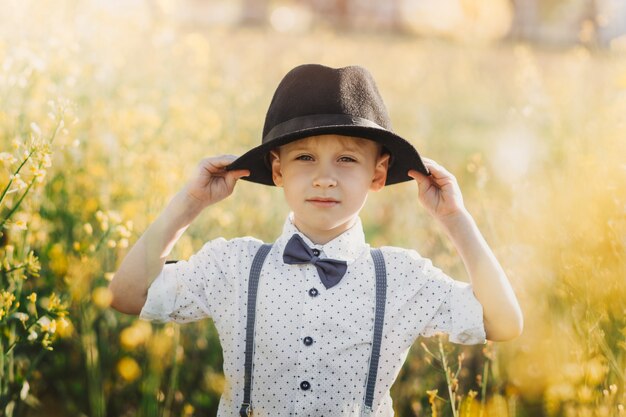 Un ragazzino con un cappello in un campo di colza. Paesaggio rurale