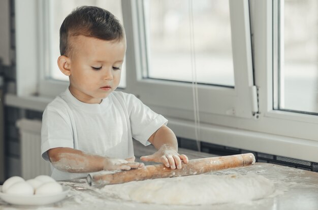 Un ragazzino con un mattarello in cucina che prepara la cottura dell'impasto