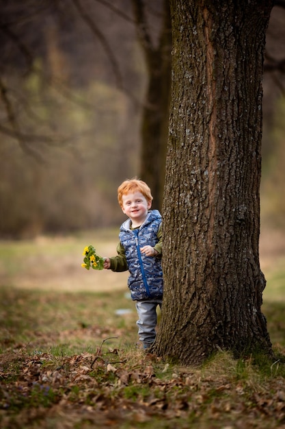 Un ragazzino dai capelli rossi si nasconde dietro un albero