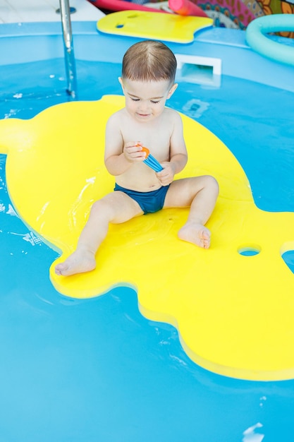 Un ragazzino di 2 anni sta imparando a nuotare in piscina Lezioni di nuoto per bambini piccoli Scuola di nuoto per bambini