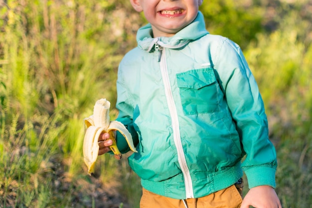 Un ragazzino di 35 anni sta mangiando una banana in natura Snack durante una passeggiata all'aria aperta