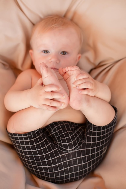 un ragazzino è sdraiato su un sedile leggero tenendo le sue piccole gambe nelle mani