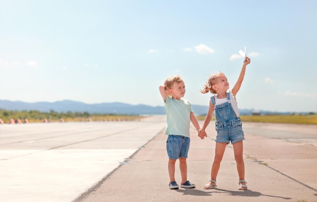 un ragazzino e una ragazza si tengono per mano e giocano con aeroplanini di carta