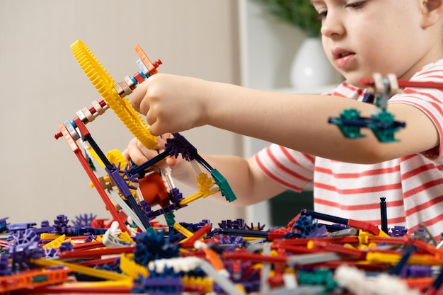 Un ragazzino gioca con un costruttore creando figure da ingranaggi e bastoni Sviluppo della logica e del pensiero nei bambini