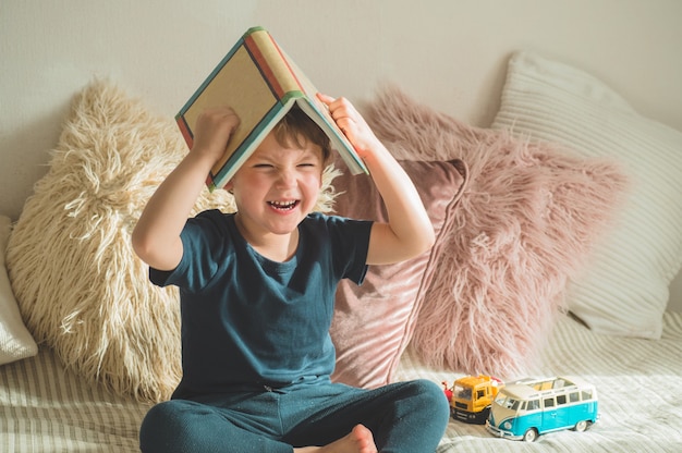 Un ragazzino si siede su un letto con un libro