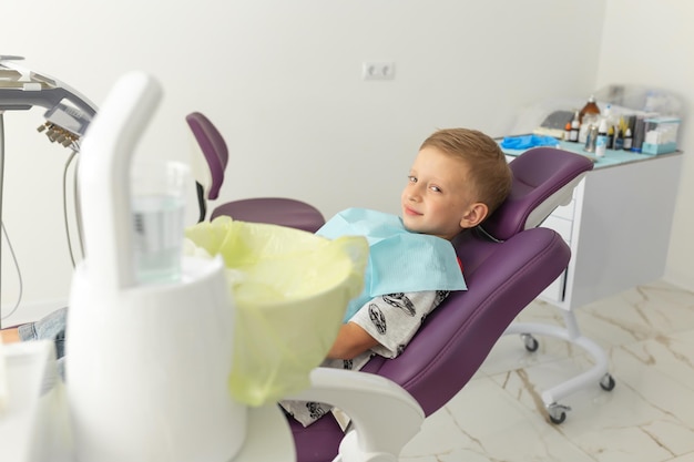 Un ragazzino sorridente e carino è seduto sulla poltrona del dentista nell'ufficio della clinica Dentista in visita con i bambini