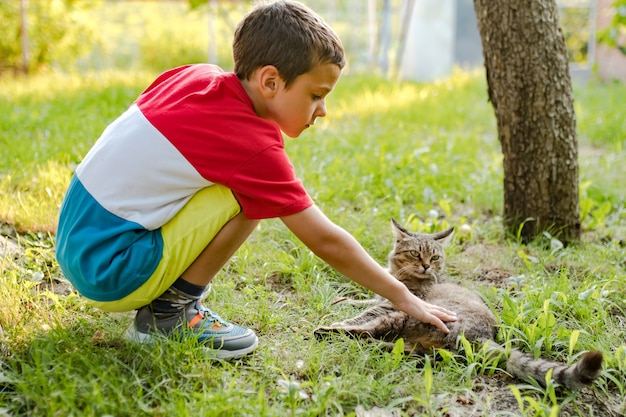 Un ragazzo accarezza un gatto in cortile