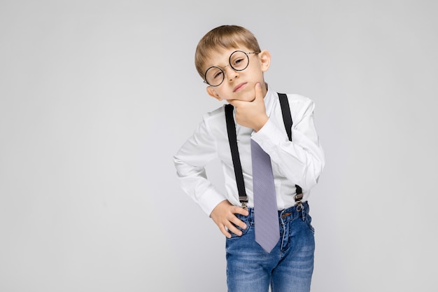 Un ragazzo affascinante con camicia bianca, bretelle, cravatta e jeans chiari