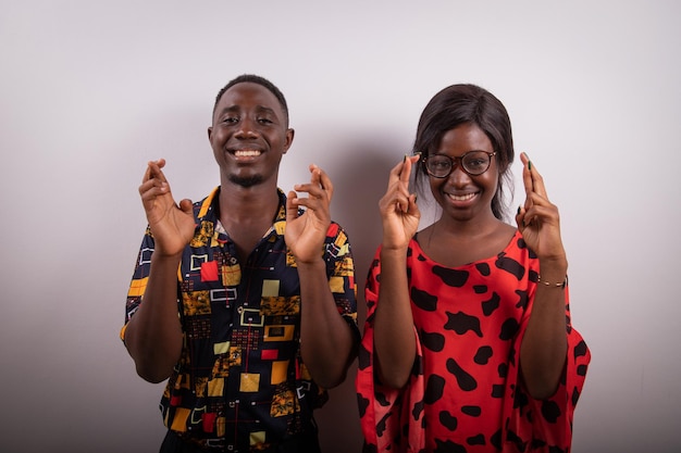 Un ragazzo africano e una ragazza con le dita incrociate studio fotografico concetto di buona fortuna e desiderio