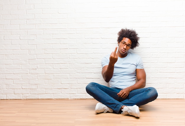 un ragazzo afro-americano seduto e lanciando il dito medio