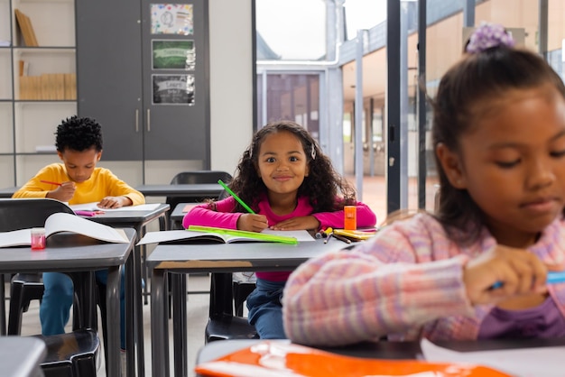 Un ragazzo afroamericano e due ragazze di due razze si sono concentrate sui loro compiti scolastici in una classe scolastica