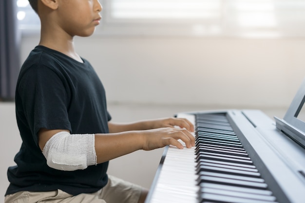 Un ragazzo asiatico alle mani ferite sta suonando il piano