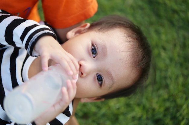 Un ragazzo asiatico sta bevendo latte in una bottiglia.