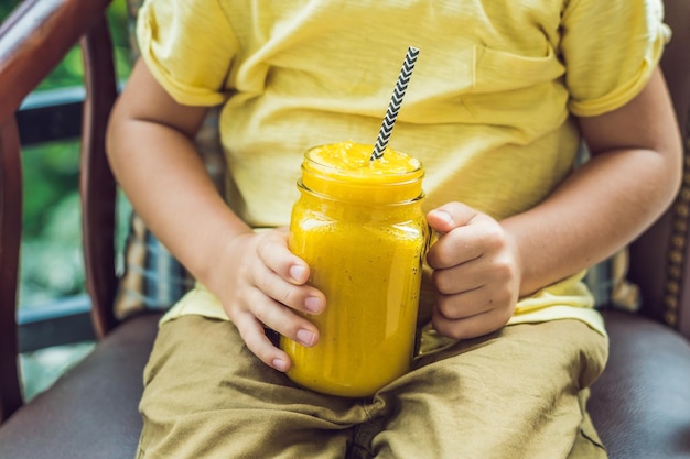 Un ragazzo beve un frullato di ananas sulla terrazza.