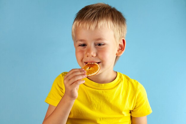 Un ragazzo biondo sorride e mangia i chip arancioni secchi