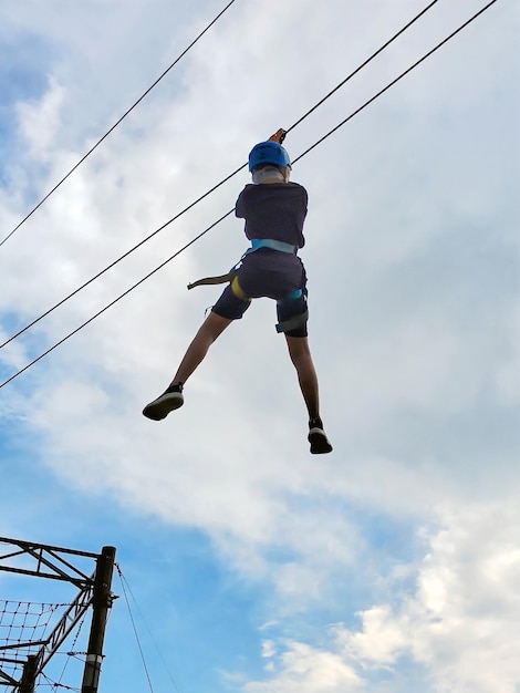 Un ragazzo caucasico adolescente in un parco divertimenti con corda scende lungo una discesa con corda Vista dal basso