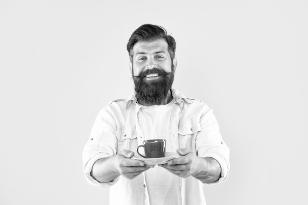 Un ragazzo caucasico felice sorride dando una tazza di tè sullo sfondo giallo bevanda calda