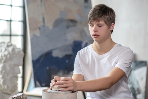 Un ragazzo che fa una pentola in uno studio d'arte