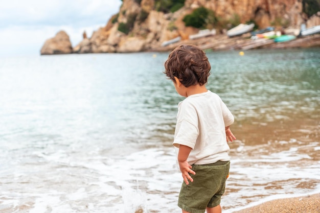 Un ragazzo che lancia sassi sulla spiaggia del porto di Sant Miquel Isola di Ibiza Isole Baleari