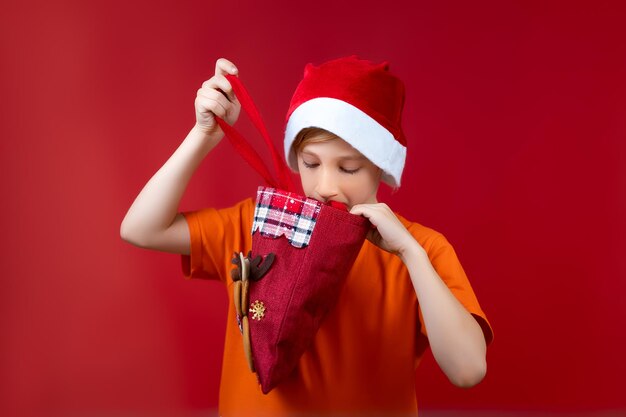 Un ragazzo con il cappello di Babbo Natale guarda in un sacchetto regalo