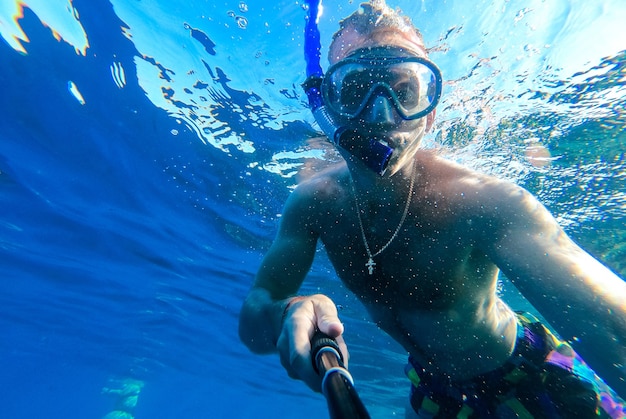 Un ragazzo con maschera e boccaglio si tuffa nelle acque azzurre del Mar Rosso e si fotografa