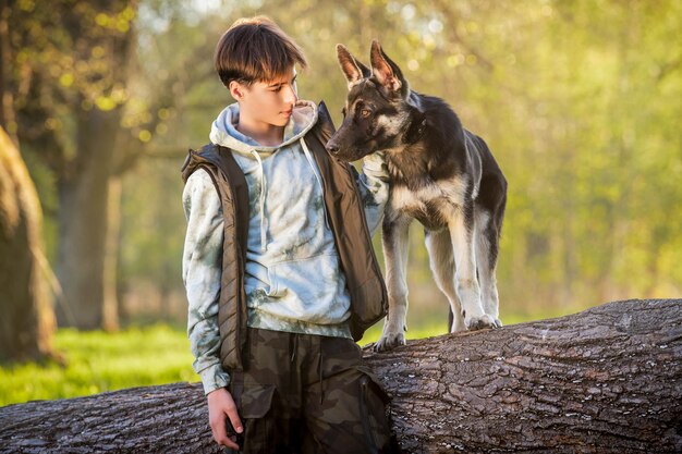 Un ragazzo con un cane cammina nel parco in una soleggiata sera primaverile seduto sull'erba Amicizia dell'uomo e dello stile di vita sano degli animali